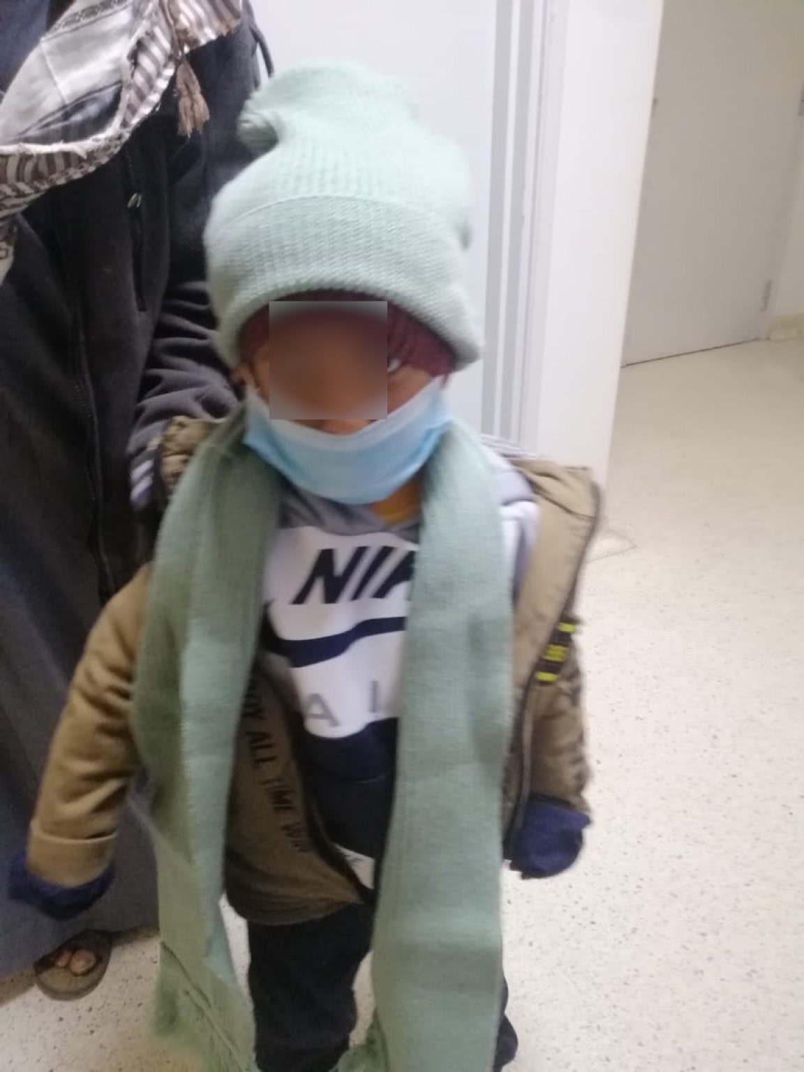 A cancer child wears wollen bonnet and a scarf